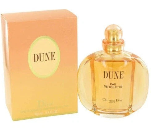 Christian Dior Dune Eau de Toilette perfume bottle next to its peach and gold gradient packaging box, set against a plain white background.