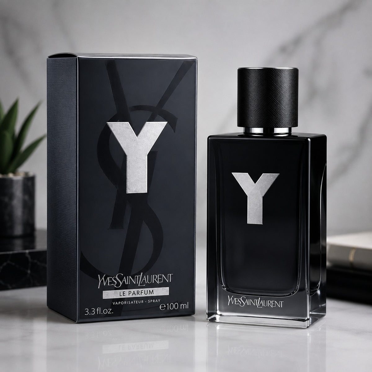 Yves Saint Laurent Le Parfum 100ml spray bottle and its black packaging box, both featuring a prominent silver 'Y' logo, set against a marble background.