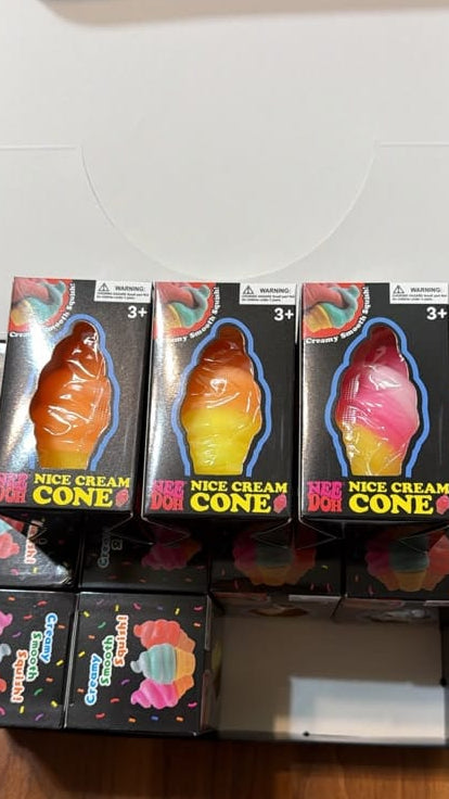 A box of 'Nice Cream Cone' novelty items displayed on a wooden table. The open white box contains several black packages featuring colorful ice cream cone graphics and the text 'NICE CREAM CONE'.