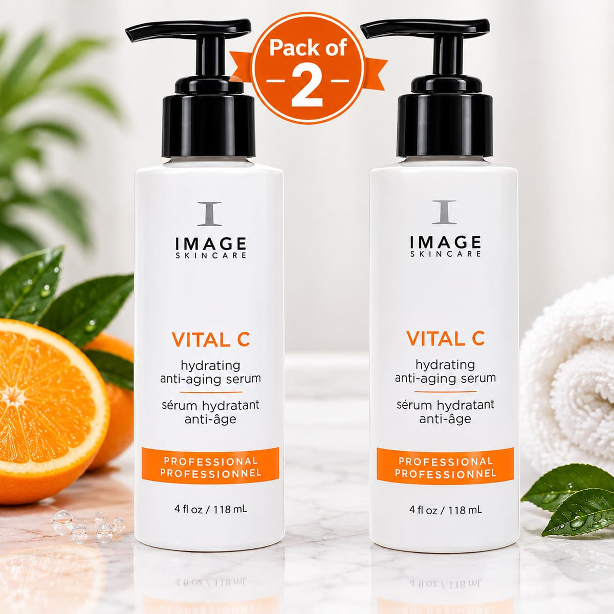 Two bottles of Image Skincare Vital C Hydrating Anti-Aging Serum arranged side by side on a marble surface with an orange half, green leaves, and a white towel in the background. A circular 'Pack of 2' badge is at the top.