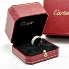 A Cartier ring displayed inside an open red presentation box, with a matching closed Cartier box in the background.