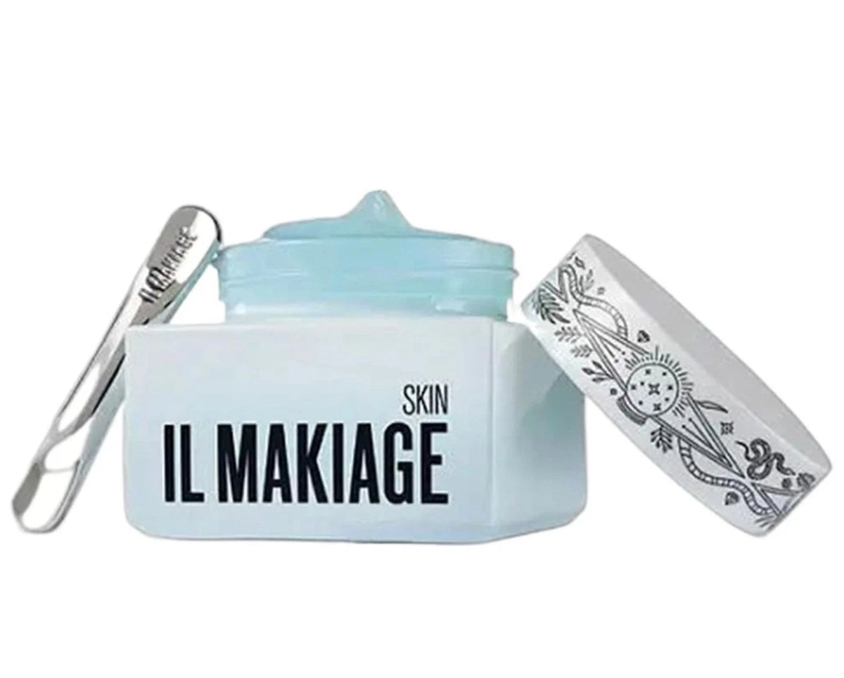 A cosmetic cream jar with its lid off, showing a light blue cream inside. The jar is white with black text reading 'IL MAKIAGE SKIN'.