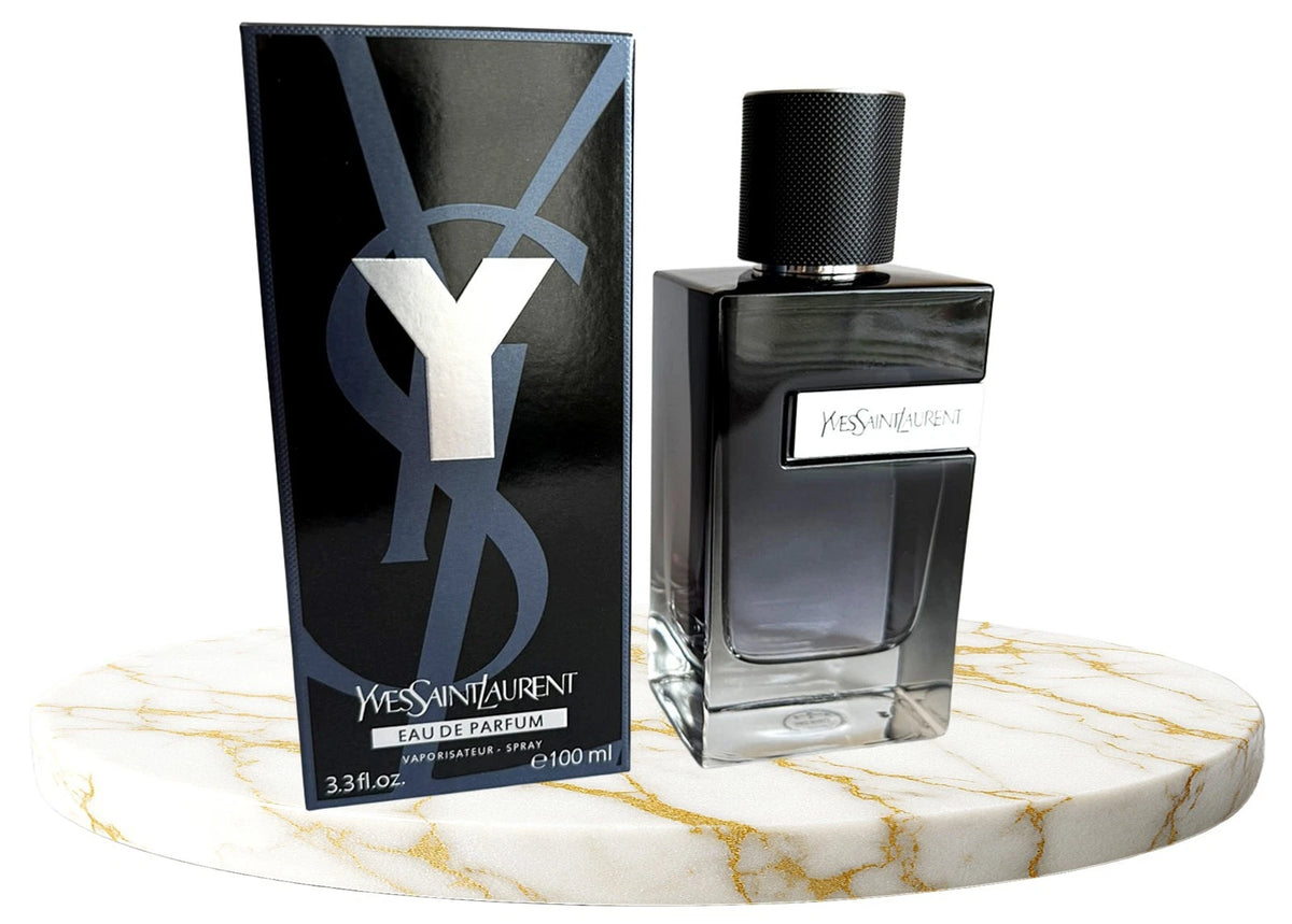 Yves Saint Laurent Eau de Parfum 100ml bottle and its black packaging box, displayed on a white marble round tray against a white background.